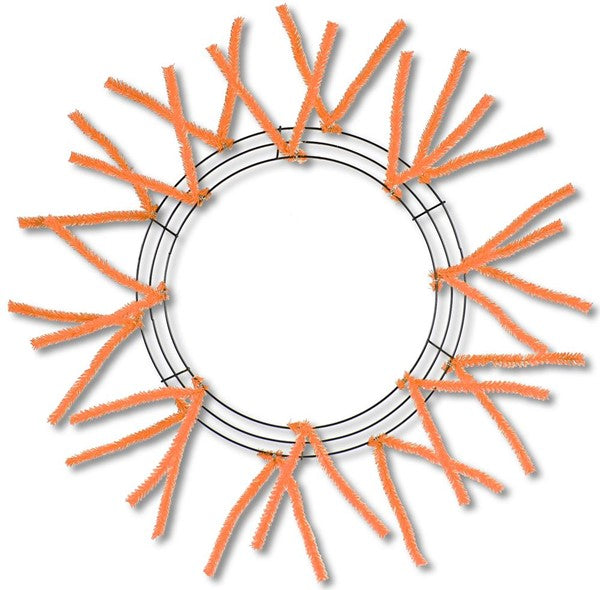 The Pencil Wreath Orange Non-Metallic 24" XX750420 features an evenly arranged round frame with multiple orange pipe cleaners radiating outward, all neatly displayed on a white background.
