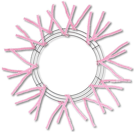 The 24" Pencil Wreath Pink Non-Metallic XX750422 features an engaging design with evenly spaced pink chenille stems radiating outward from a circular base, creating a vibrant sunburst pattern. This cheerful design adds a joyful touch to any space, reminiscent of a blooming flower or bright star.