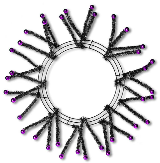 The 24 Black Metallic Pencil Wreath XX751564 features spiky tinsel branches tipped with shiny purple balls, creating a striking starburst effect on a white background.