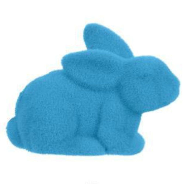 The 8.5L x 6H Flocked Laying Rabbit in assorted vibrant colors like purple, pink, black, green, orange, and turquoise resembles a soft toy. Crafted from polystyrene/nylon, its bold hue contrasts with a plain white background, accentuating its whimsical charm.