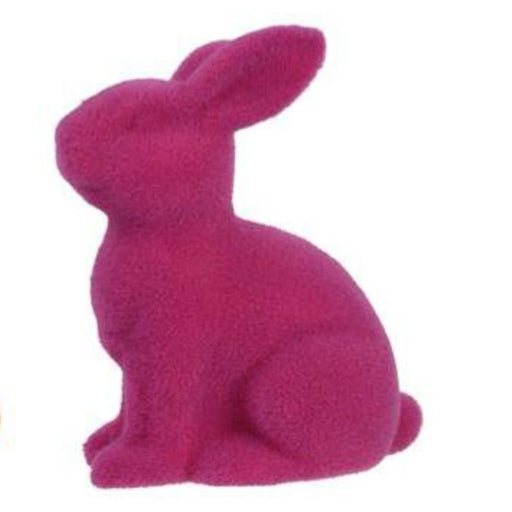 The 10H x 8.25L flocked sitting rabbit figurine, made of polystyrene and nylon in fuzzy pink with upright ears, is displayed against a white background.