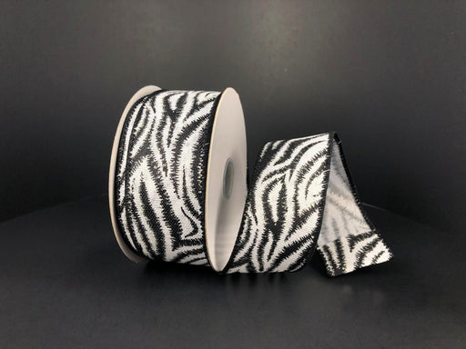 A partially unwound roll of White Linen/Black-Silver Zebra Print Ribbon, sized 1.5x10y, lies on a dark surface, showcasing its distinctive synthetic and wired design for a striking contrast.
