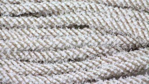 Close-up of coiled Deco Flex Tubing Snowdrift RE3221CC. It displays a fuzzy, braided texture with white and beige hues, showcasing the intricate fiber weave—ideal for elegant gift wrapping.