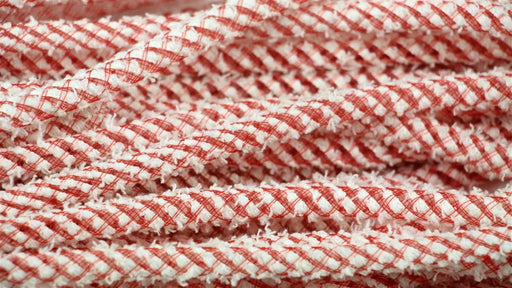 A close-up of intertwined Deco Flex Tubing Red and White Snowdrift (RE3221G2) ropes, featuring a textured, braided pattern. Reminiscent of festive creations, these ropes fill the frame with their intricate design, arranged randomly.