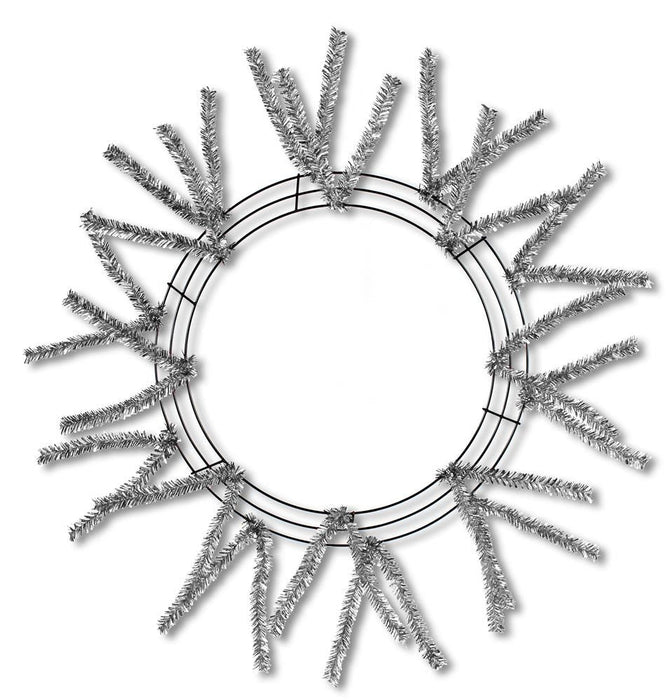 The Pencil Work Wreath 24" Metallic Silver XX751126 features metallic silver pine branches radiating outward like sun rays against a plain white background.