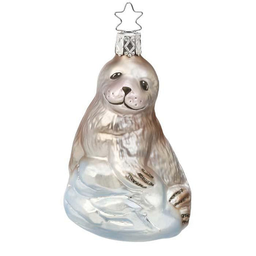 The Sea Pup Christmas Ornament Inge-Glas 1-089-15 is a mouth-blown glass ornament featuring a smiling seal on icy blue waves with a silver star hanger—a charming addition to any heirloom ornament collection.