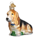 The Basset Hound Old World Christmas Ornament 12473 is a beautifully crafted glass piece in the shape of a basset hound sitting on lush green grass. It features intricate coloring and has a small gold cap at the top, making it perfect for hanging.