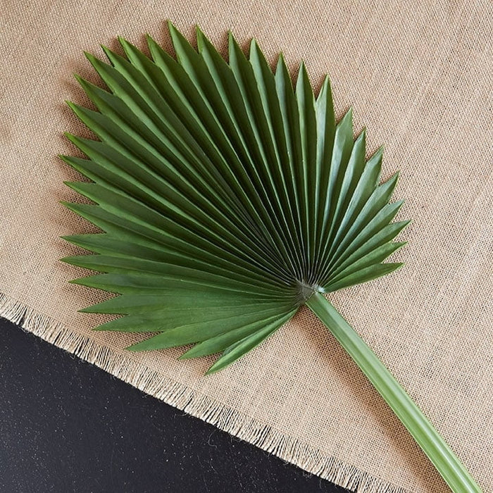 A single RAZ Leaf Stem from the Botanical Collection rests on beige burlap with frayed edges, displayed against a black background.