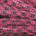 Close-up of intertwined Deco Flex Tubing Black Fuchsia Stripe Metallic Foil RE3010K7, featuring shiny pink and black crisscross patterns for a textured, vibrant look—ideal for holiday creations.