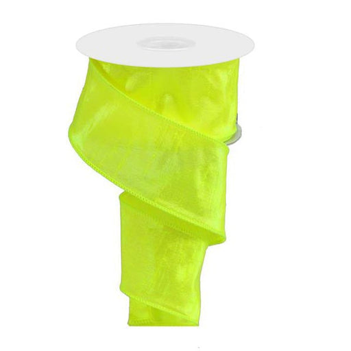 The 2.5 Chartreuse Iridescent Dupioni Ribbon (RG01965FY) spirals gracefully from its spool, with metallic wired edges for added structure and a sleek white top.